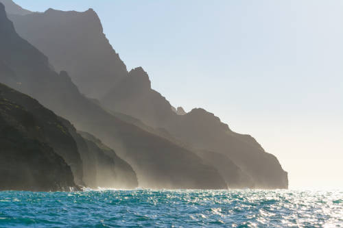 Ocean mist rises around the Na Pali coast in Kauai island, Hawaii.