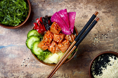 Hawaiian salmon poke bowl with seaweed watermelon radish cucumber pineapple and sesame seeds.