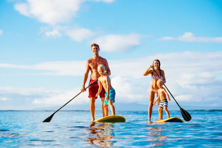 A family enjoys a session of paddle boarding, the perfect activity for small groups touring Hawaii.