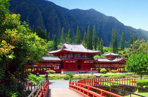 The bright red Byodo-in Buddhist Temple nestles against the lush greenery and blue mountains of Oahu Hawaii.