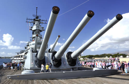 Tourists appear miniscule under the towering guns of the U.S.S. Missouri, a favorite destination visited in our private Pearl Harbor tours.