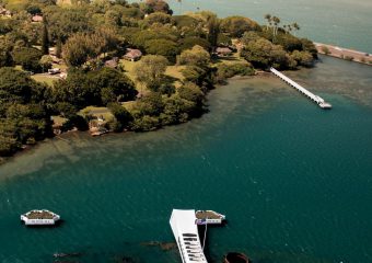 An aerial view of Pearl Harbor shows the USS Arizona Memorial surrounded by natural beauty, a site visited in our private Pearl Harbor tours.